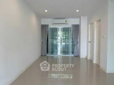 Spacious empty living room with glossy tiled floor and large glass doors.