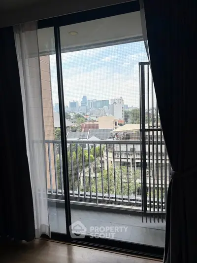 Stunning city view from a modern apartment balcony with floor-to-ceiling glass doors.