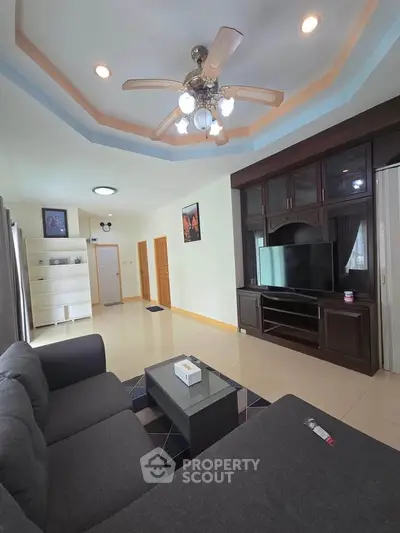 Spacious living room with modern decor and entertainment center, perfect for relaxation and gatherings.