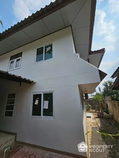 Newly constructed two-story home with a modern design, featuring crisp white exterior walls and multiple windows for ample natural light, set in a developing neighborhood.