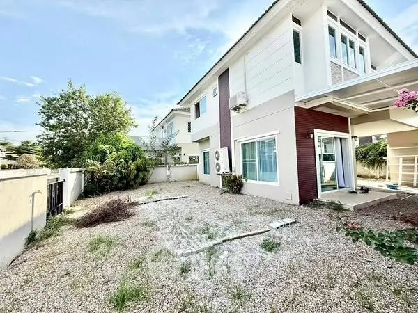 Spacious modern two-story house with large gravel yard and lush greenery.