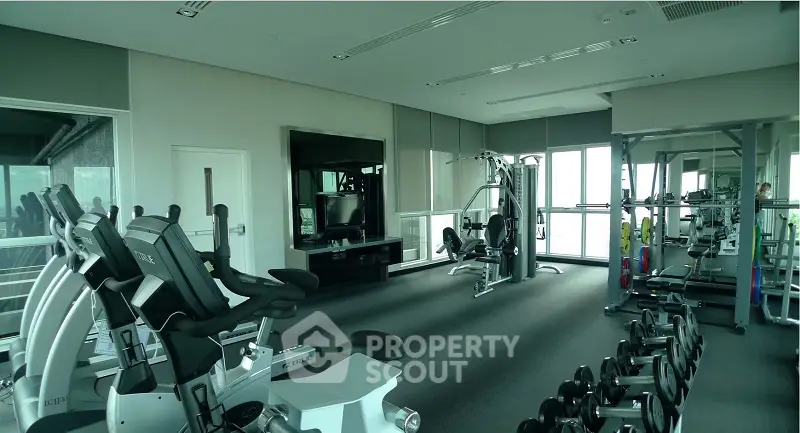 Modern gym with state-of-the-art equipment and panoramic windows in luxury building.
