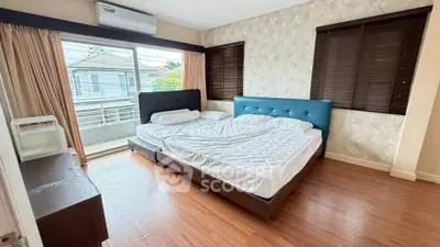 Spacious bedroom with large windows and modern decor, featuring a comfortable bed and wooden flooring.