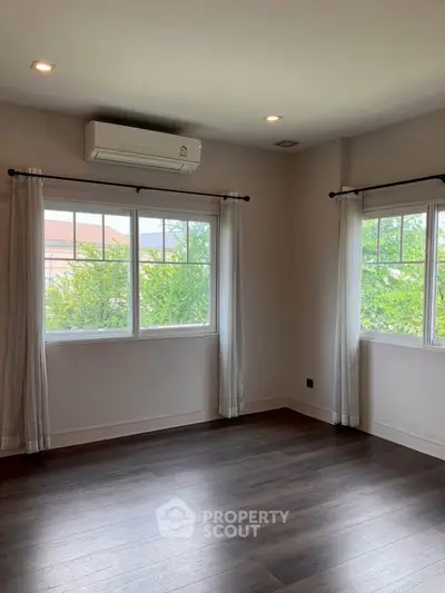 Spacious empty room with large windows and air conditioning, perfect for customization.