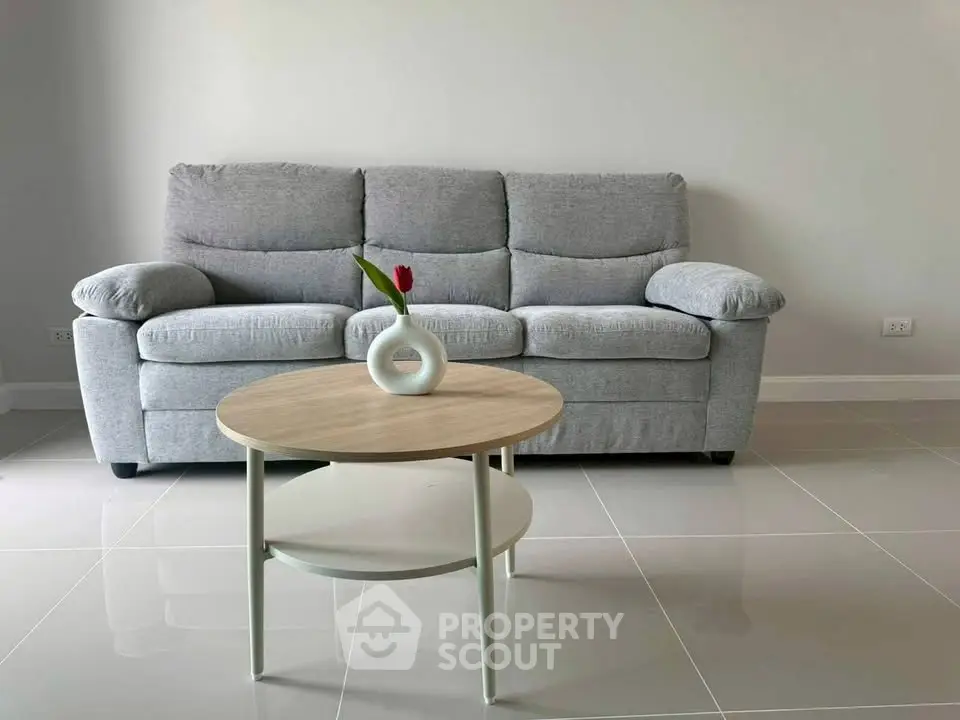 Modern living room with stylish gray sofa and minimalist coffee table on sleek tiled floor.