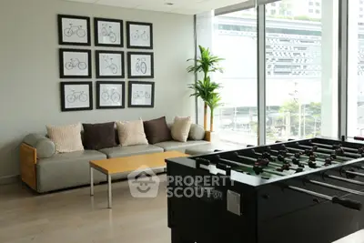 Modern living room with foosball table and large windows in a stylish apartment.