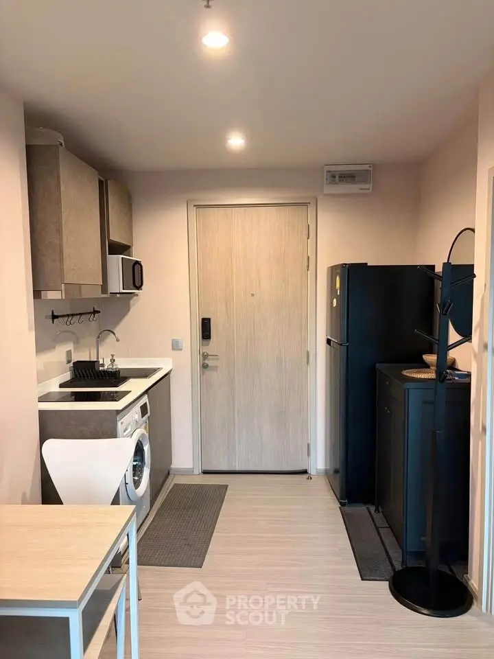 Modern compact kitchen with washing machine and fridge in cozy apartment