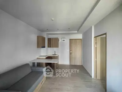 Modern minimalist living room with open kitchen layout and sleek wooden finishes.