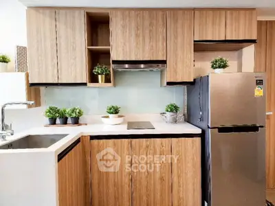 Modern kitchen with sleek wooden cabinets and stainless steel fridge, perfect for contemporary living.