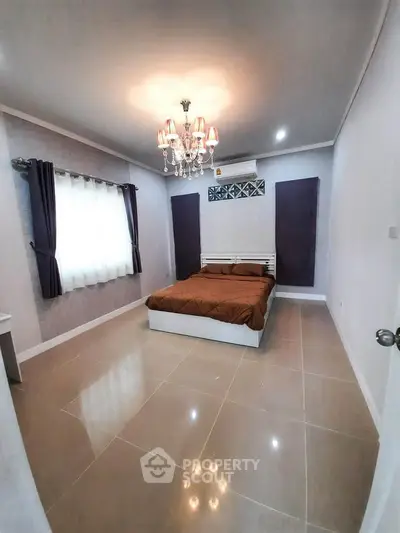 Spacious bedroom with elegant chandelier and modern decor