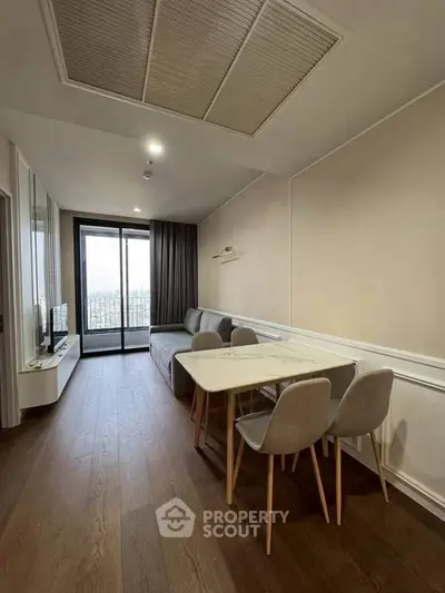 Modern living room with dining area and city view balcony, featuring sleek furniture and elegant design.