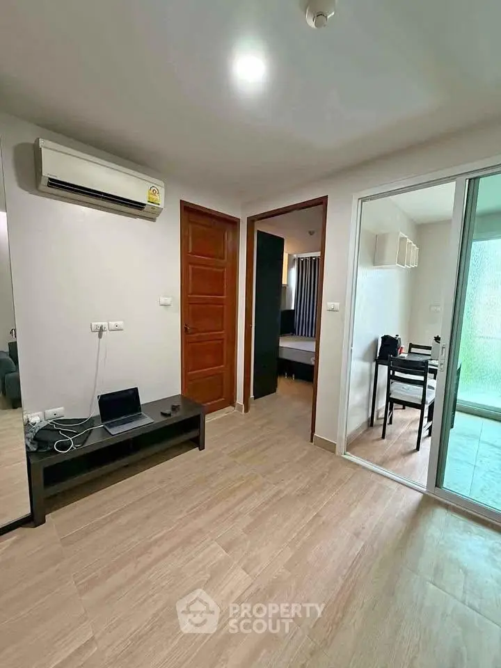 Modern apartment interior with wooden flooring, air conditioning, and sliding glass doors leading to a cozy dining area.