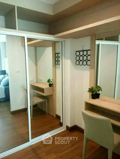 Modern bedroom with mirrored wardrobe and wooden flooring