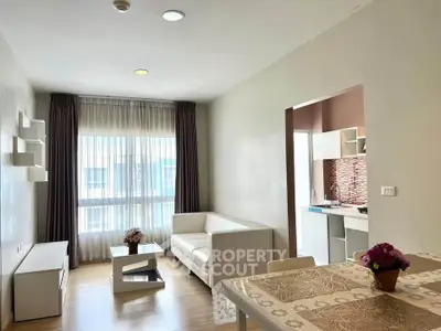 Modern living room with open kitchen, featuring elegant decor and natural light.