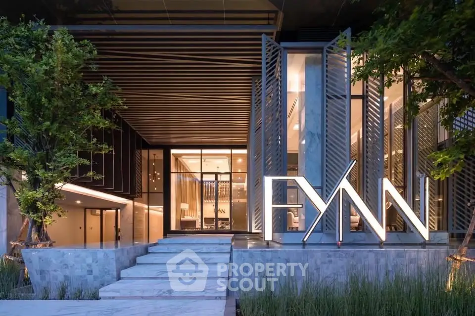 Modern building entrance with sleek design and illuminated signage, showcasing luxury real estate appeal.
