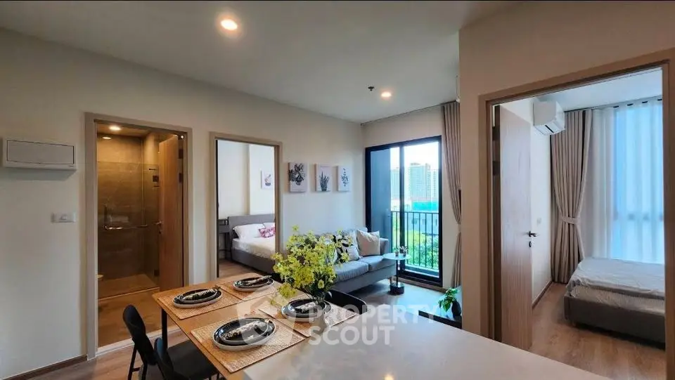 Modern apartment interior with open layout, featuring dining area, living room, and bedroom with city view.