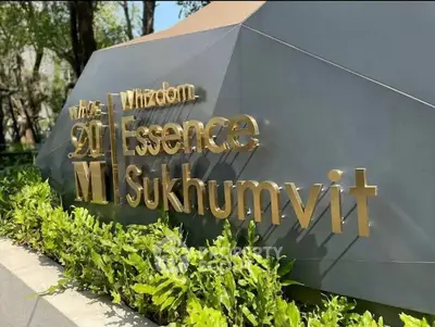 Luxurious Whizdom Essence Sukhumvit entrance sign surrounded by lush greenery.