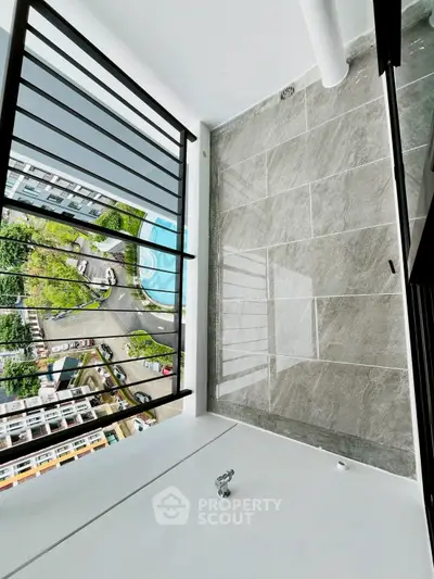 Modern balcony with sleek railing and city view, overlooking pool and greenery.