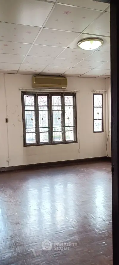 Spacious empty room with parquet flooring and large windows