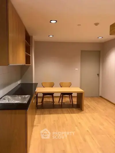 Modern kitchen with wooden cabinets and dining area in a cozy apartment.