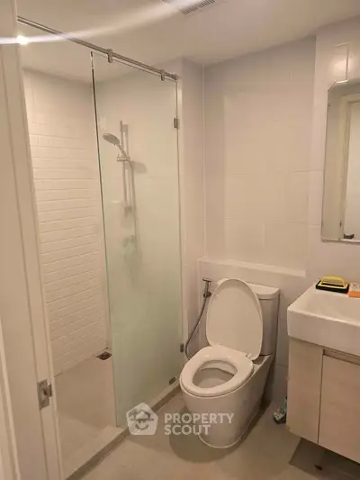 Modern bathroom with glass shower and sleek fixtures in a contemporary apartment.