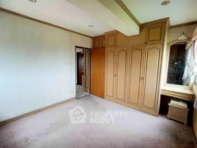 Spacious bedroom with built-in wooden wardrobe and vanity, ideal for customization.