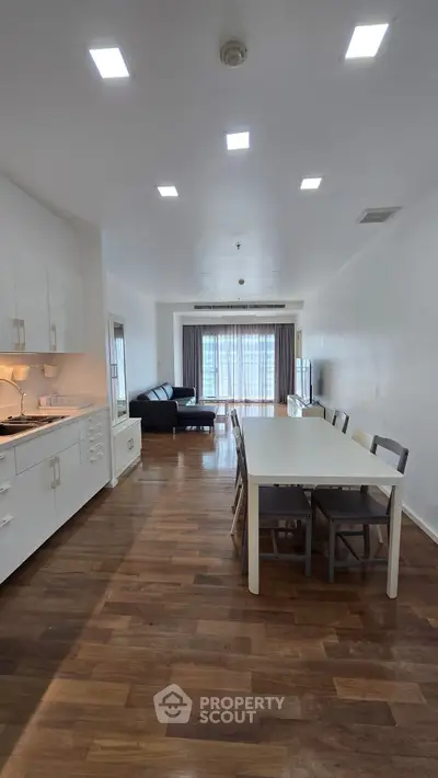 Spacious open-plan living and dining area with modern furnishings and wooden flooring.