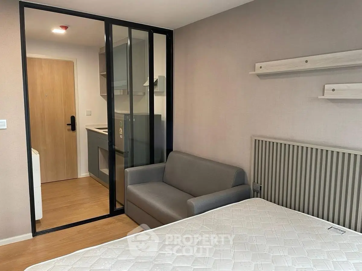 Modern studio apartment with compact kitchen and cozy living area, featuring sleek sliding glass doors.