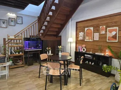 Charming living room with wooden staircase, aquarium, and cozy dining area.