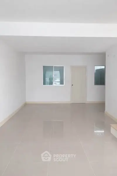 Spacious empty room with glossy tiled floor and white walls, ideal for customization.