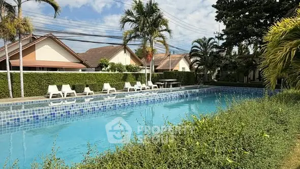 Luxurious outdoor pool area with lush greenery and sun loungers in a serene residential setting.