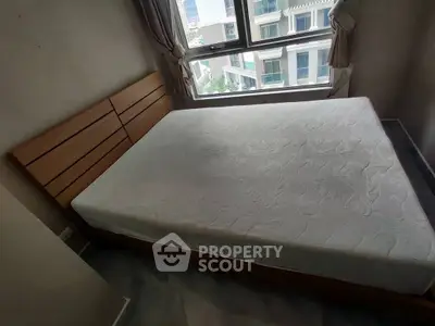 Cozy bedroom with large window offering city view, featuring a comfortable bed and elegant curtains.