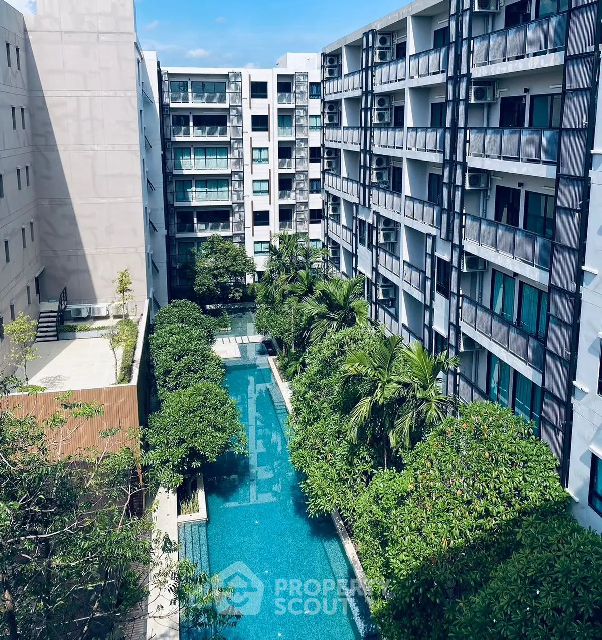 Modern apartment complex with lush greenery and inviting swimming pool view.