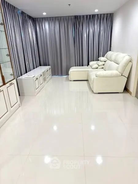 Spacious living room with elegant white sofa and floor-to-ceiling curtains