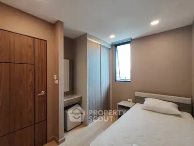 Modern bedroom with sleek design, featuring a comfortable bed, built-in wardrobe, and natural light from a large window.