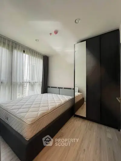 Modern bedroom with large window and sleek wardrobe in a stylish apartment.