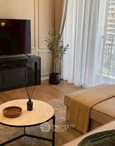 Elegant living room with modern decor, large TV, and cozy seating area near a window with city view.