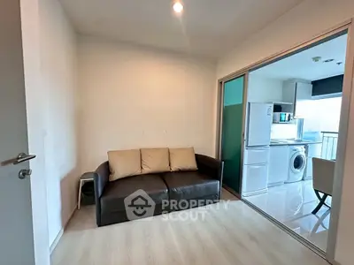 Modern apartment with cozy living area and adjacent kitchen featuring appliances