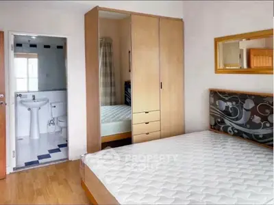 Cozy bedroom with wooden wardrobe and ensuite bathroom in modern apartment