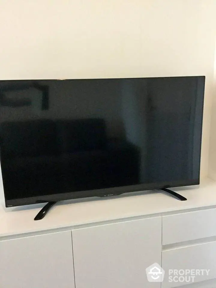 Modern living room with sleek flat-screen TV on white cabinet