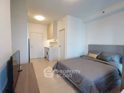 Modern studio apartment with cozy bedroom and compact kitchen area.