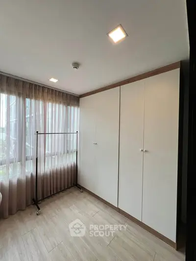 Spacious bedroom with large windows and ample closet space in modern apartment.