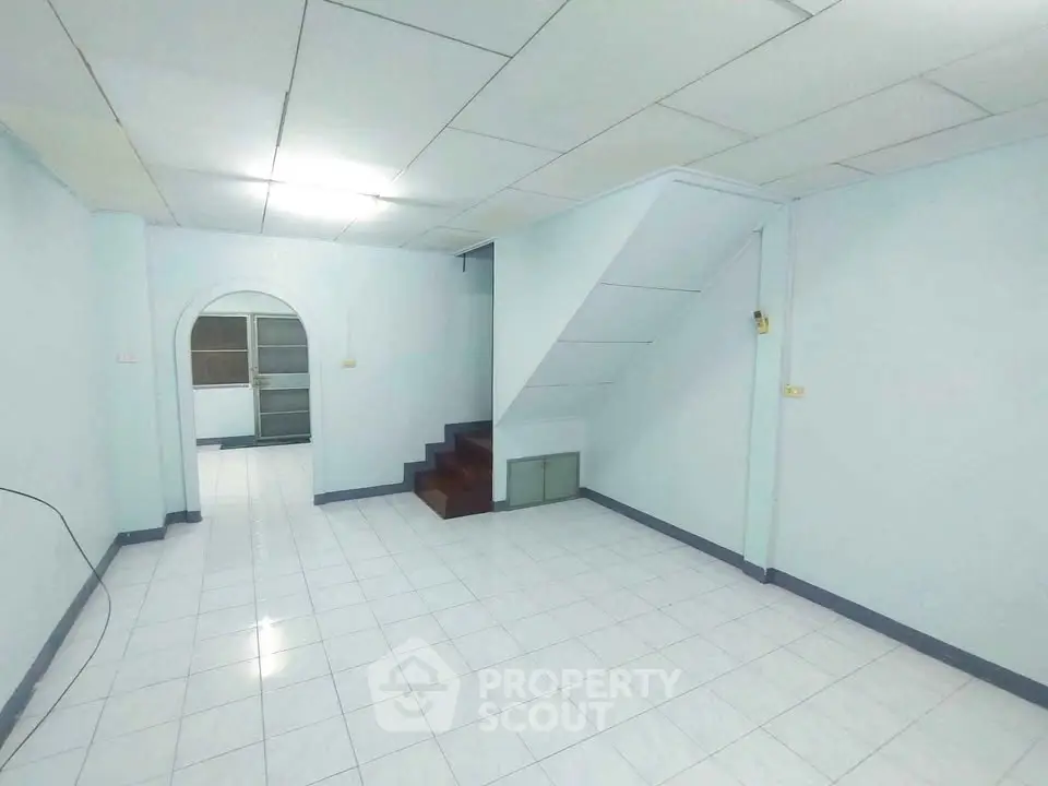 Spacious interior with tiled flooring and staircase, ideal for customization.