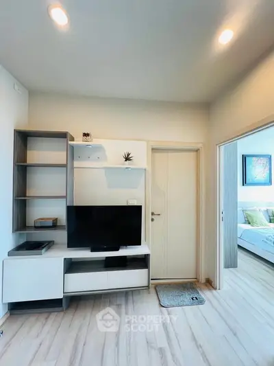 Modern living room with sleek TV unit and view into cozy bedroom