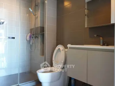Modern bathroom with glass shower and sleek vanity in contemporary apartment.