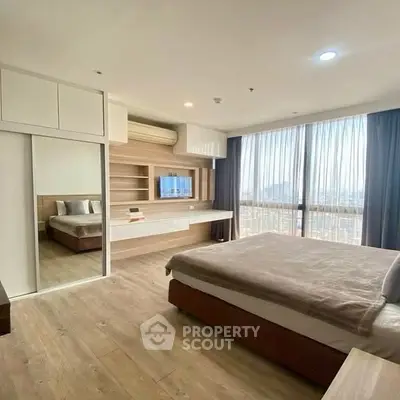 Spacious modern bedroom with large windows and wooden flooring