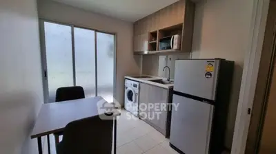 Compact kitchen with washing machine and dining area in modern apartment.