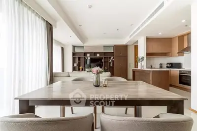 Modern open-plan living room and kitchen with elegant dining area and natural light.