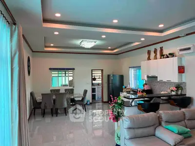 Spacious open-plan living room with modern kitchen and dining area, featuring elegant decor and ample natural light.