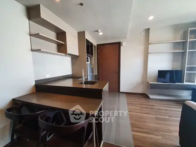 Modern open-layout kitchen and living area with sleek design and wooden flooring.